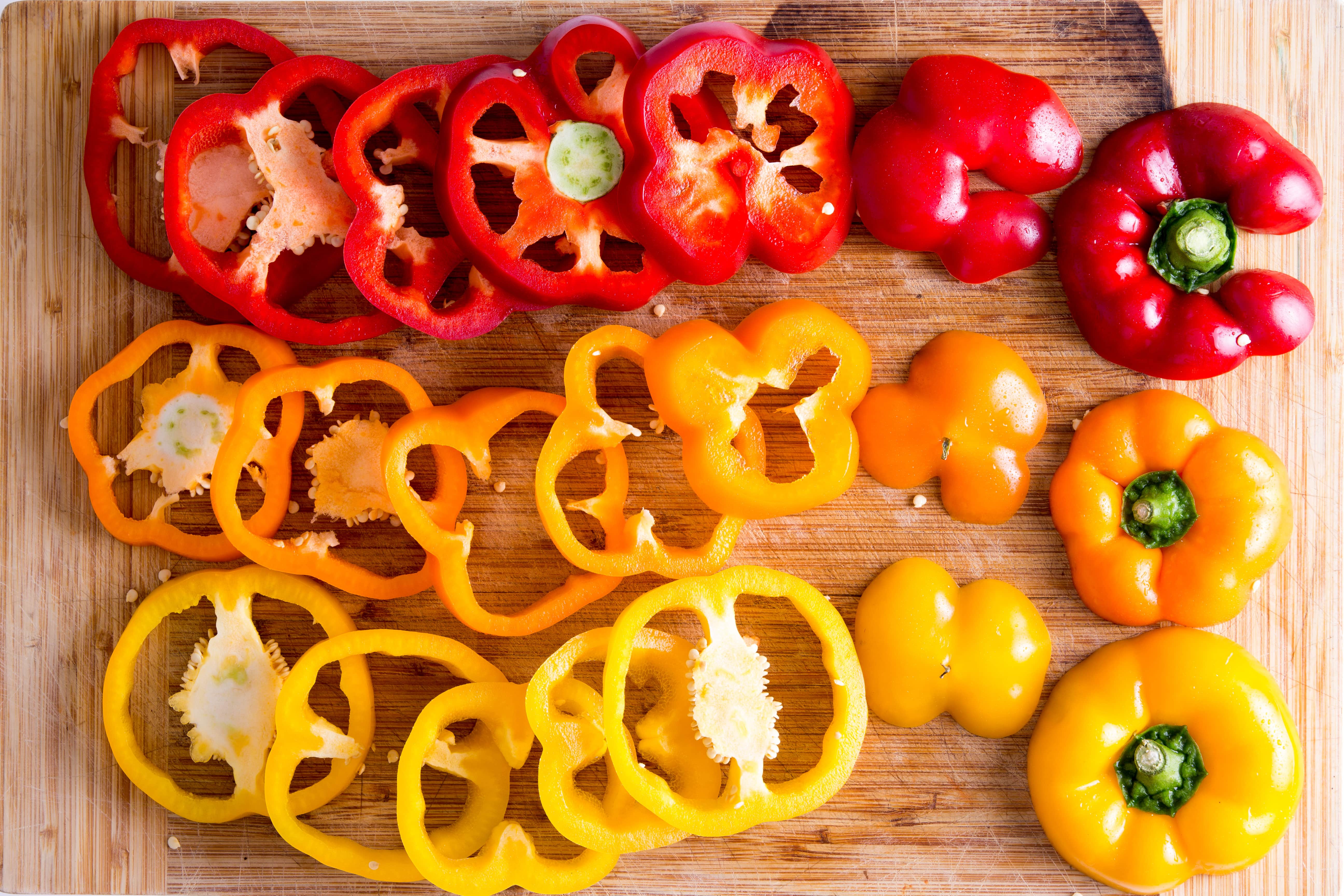 Red, orange, and yellow Bell Peppers on a cutting board