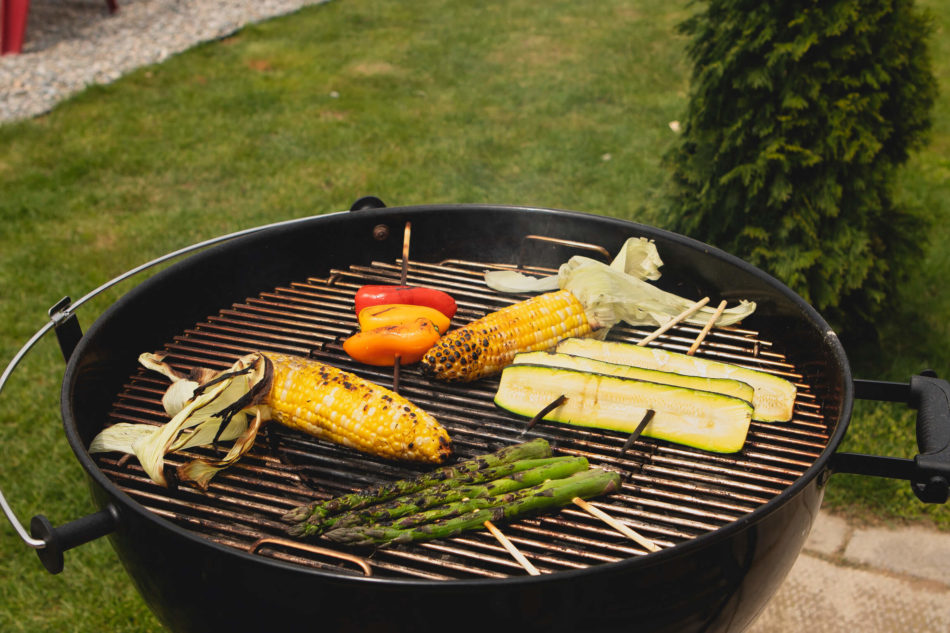 Grilling corn on the cob, asparagus, zucchini, and mini sweet peppers on a charcoal grill