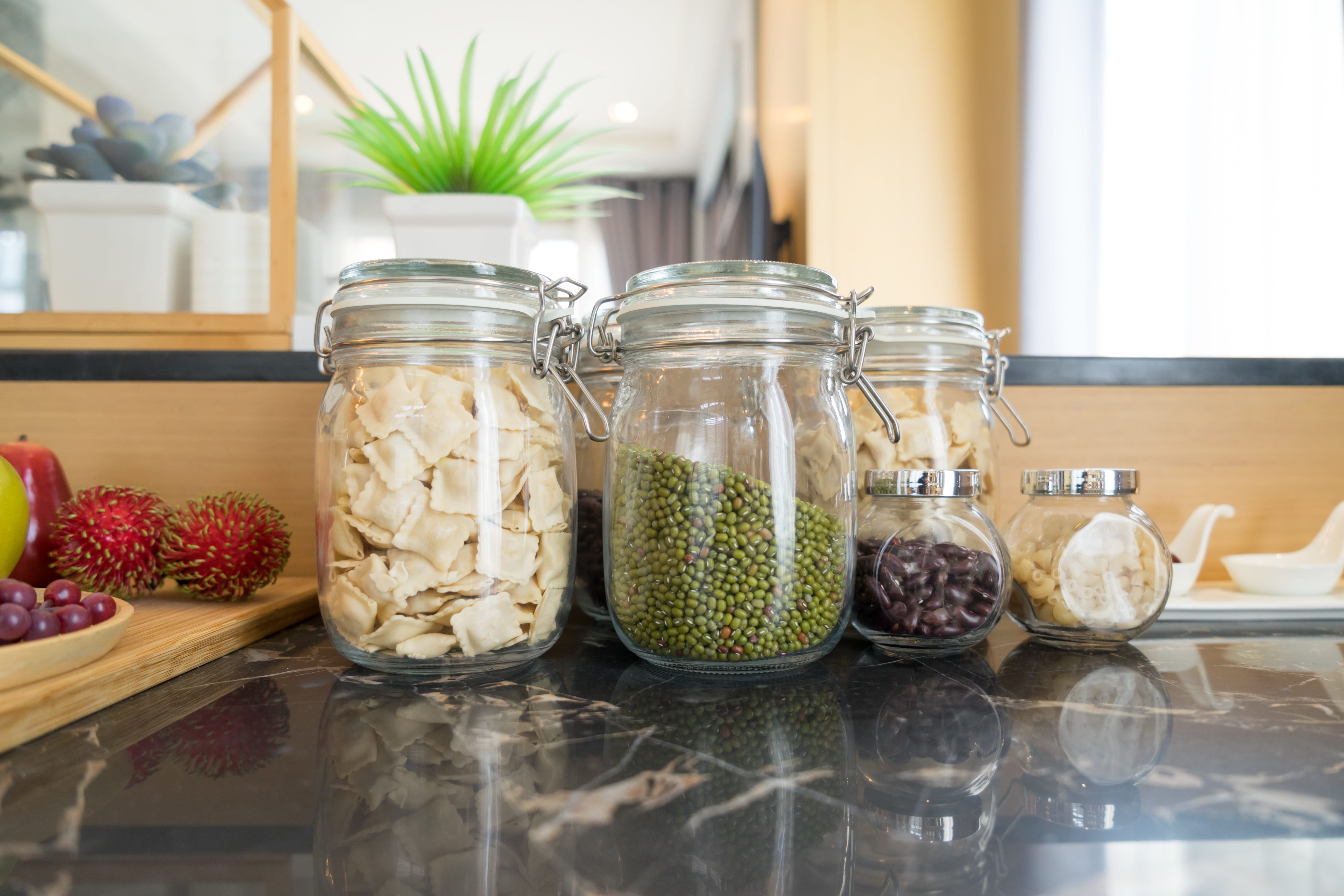 Green bean, red bean, macaroni, pasta in glass jars on a counter top
