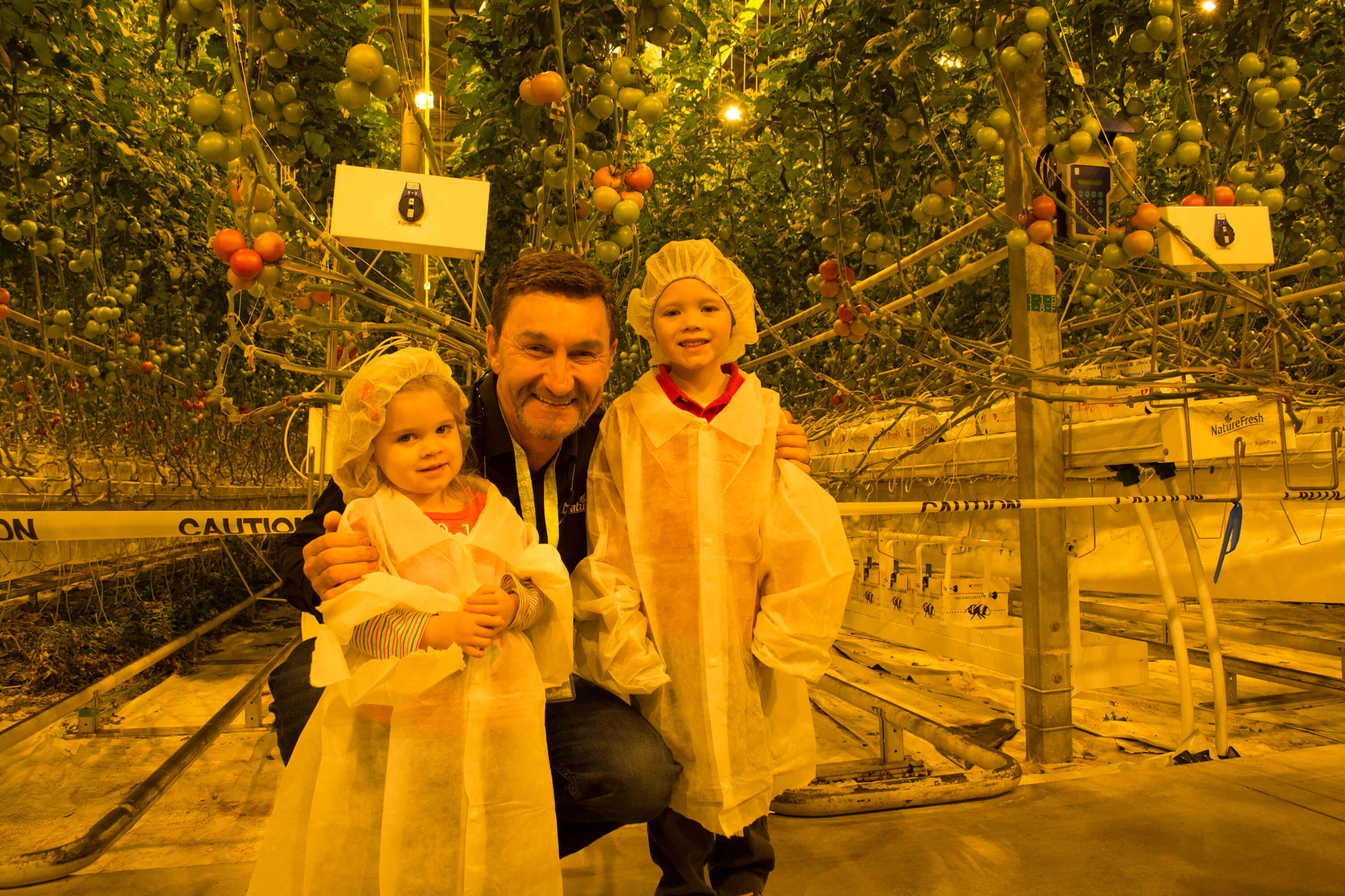 Peter Quiring, Owner & President of NatureFresh Farms poses with children in the greenhouse