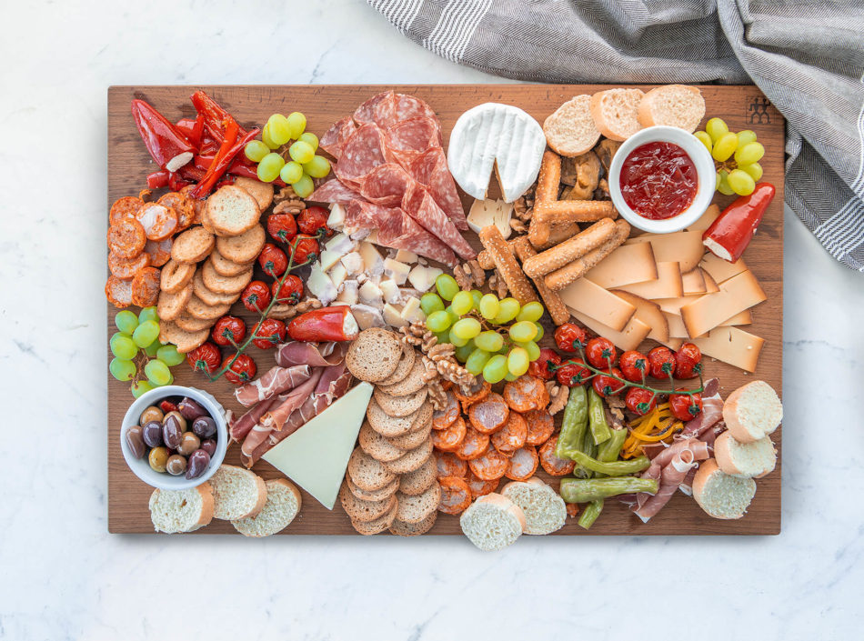 A charcuterie board loaded with fresh veggies, meats, cheeses, and breads