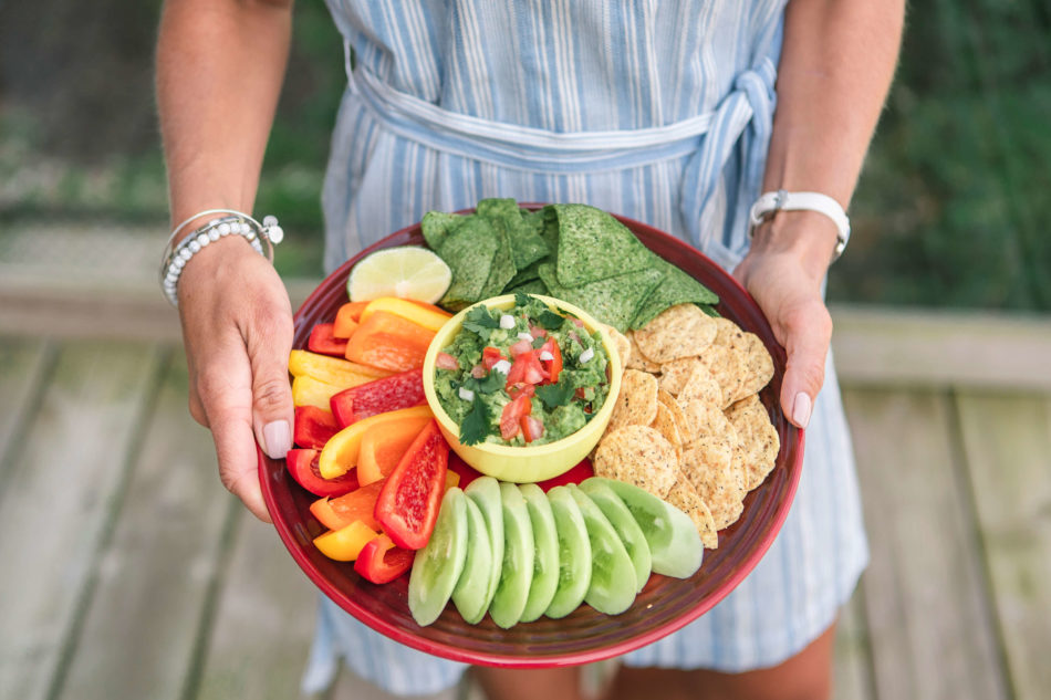 Woman holding fresh guacamole snack tray