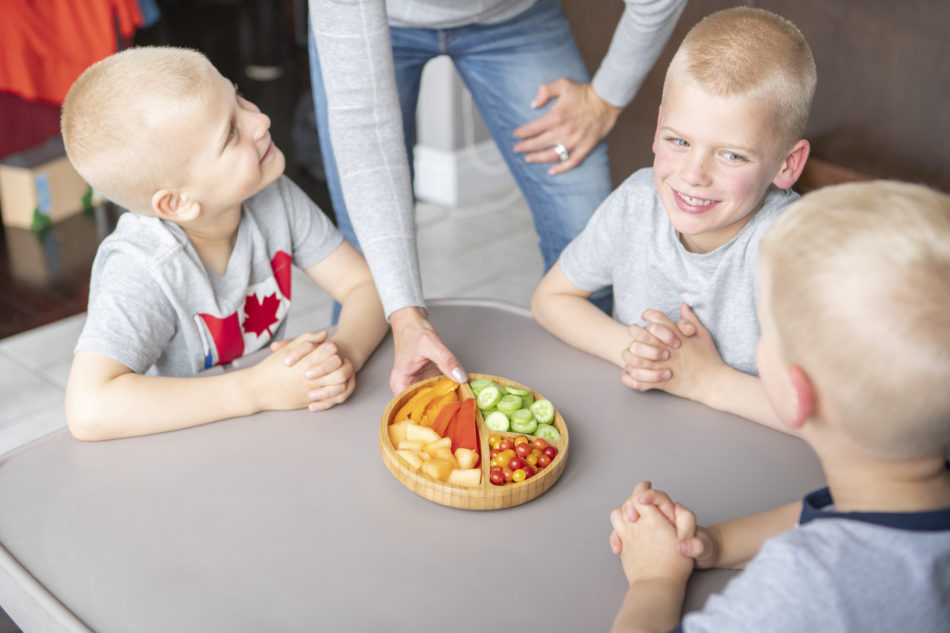 Young children being served a veggie tray