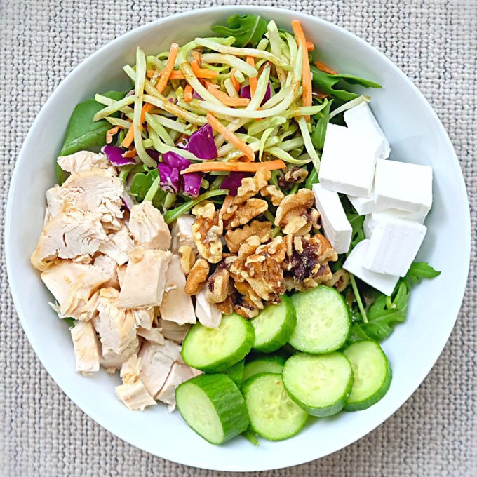 Arugula, broccoli and carrot slaw, NatureFresh™ Farms Long English Cucumbers, roasted chicken, walnuts and vegan feta, and dijon balsamic dressing to top.