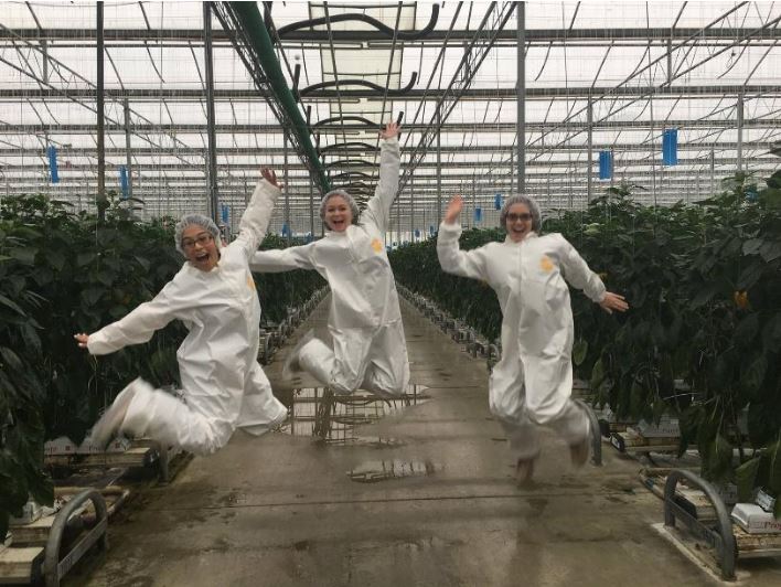 Three girls jumping happily in a greenhouse