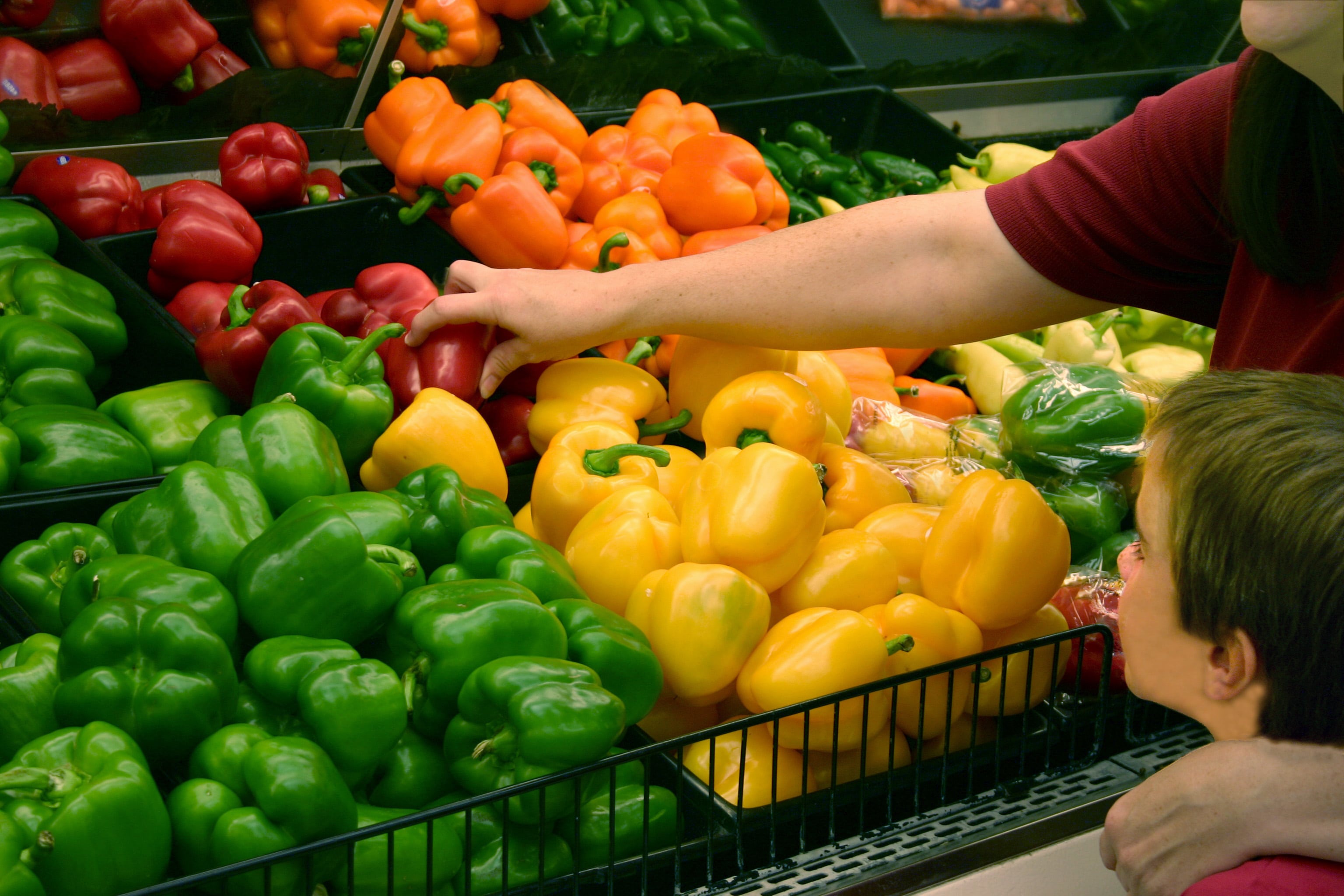 Picking bell peppers from the shelf at the grocery store
